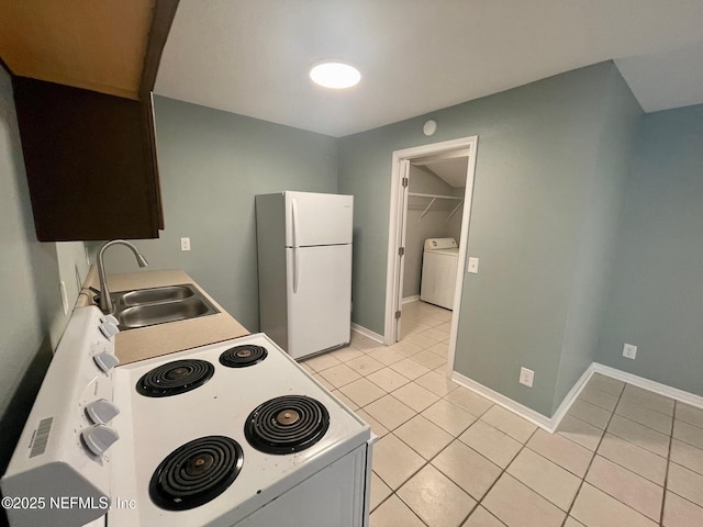 kitchen with light tile patterned flooring, white appliances, a sink, and washer / dryer