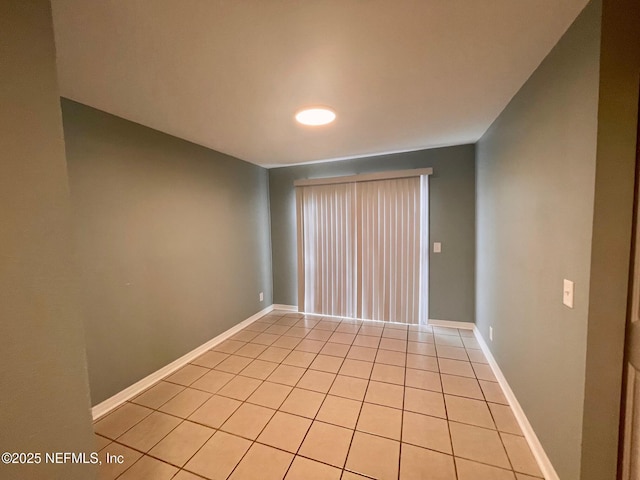 spare room with baseboards and light tile patterned floors