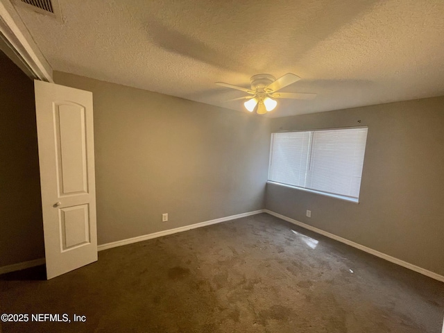 spare room featuring a ceiling fan, a textured ceiling, carpet floors, baseboards, and visible vents