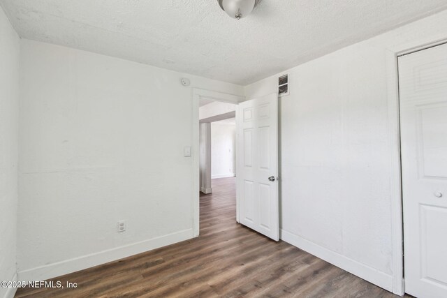 1330 Barnett St, Jacksonville, FL 32209 - unfurnished bedroom featuring a closet, baseboards, visible vents, a textured ceiling, and dark wood-style floors