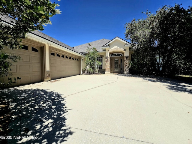 view of front of house with an attached garage, stone siding, and concrete driveway