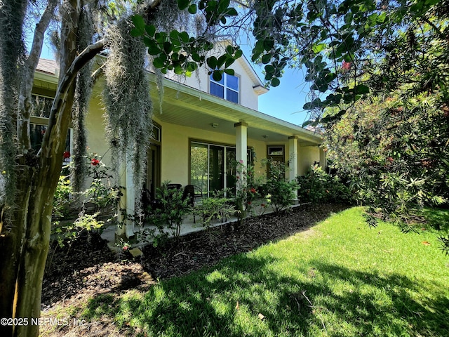 view of side of home with a lawn, a patio area, and stucco siding