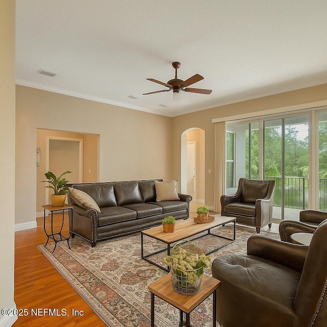 living area with ceiling fan, arched walkways, baseboards, wood finished floors, and visible vents