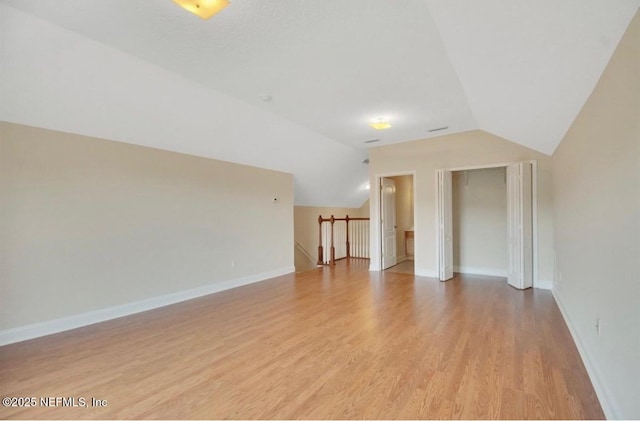 bonus room featuring baseboards, light wood finished floors, and lofted ceiling