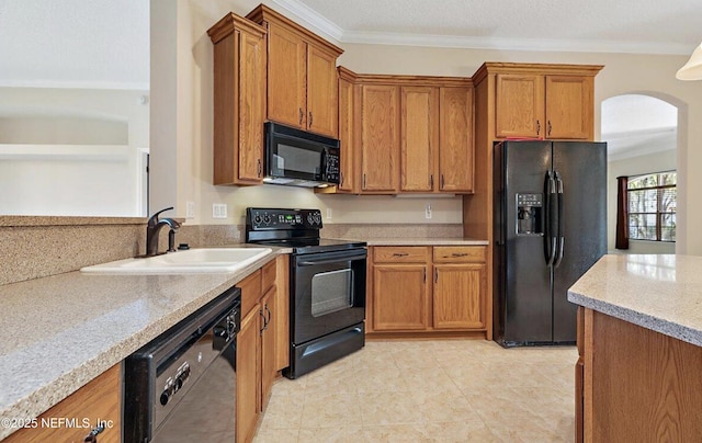 kitchen featuring brown cabinetry, arched walkways, a sink, light tile patterned floors, and black appliances