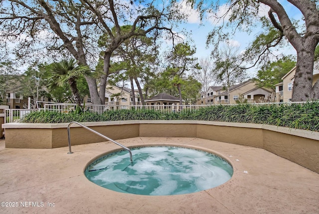 view of swimming pool featuring fence and a hot tub