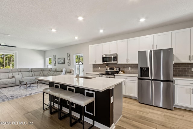 kitchen with light countertops, appliances with stainless steel finishes, open floor plan, and a sink
