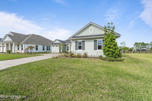 ranch-style home featuring fence, driveway, and a front lawn