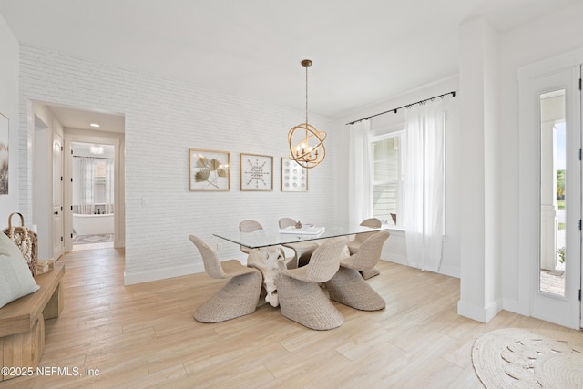 dining space featuring baseboards, light wood-style floors, and a notable chandelier
