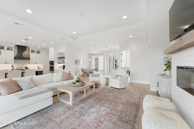 living room featuring recessed lighting, light wood-style flooring, and a glass covered fireplace