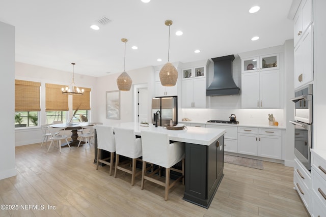 kitchen featuring appliances with stainless steel finishes, light countertops, premium range hood, decorative backsplash, and visible vents