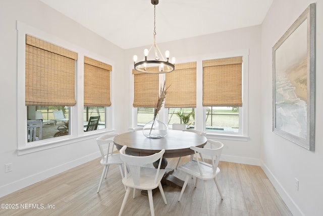 dining room featuring baseboards, light wood finished floors, and a chandelier