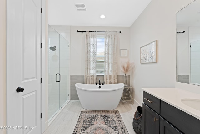 bathroom featuring vanity, recessed lighting, a freestanding tub, tile walls, and a stall shower