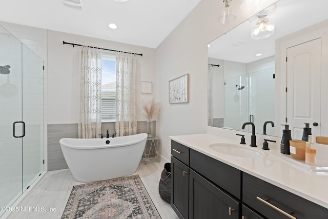 bathroom with vanity, a soaking tub, a shower stall, and recessed lighting