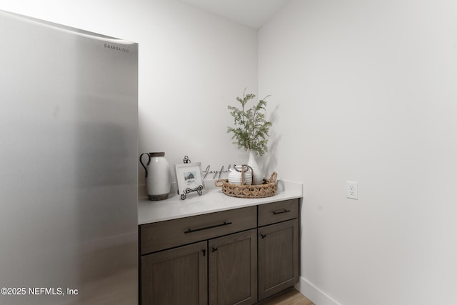 bar featuring freestanding refrigerator and baseboards