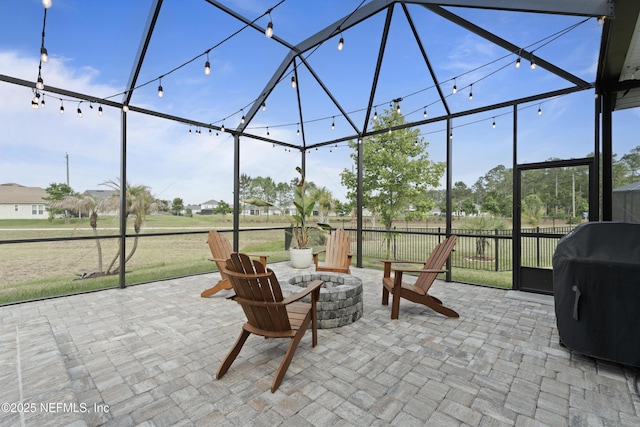 view of patio with a fire pit, a lanai, fence, and a grill