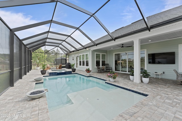 view of pool featuring a ceiling fan, glass enclosure, a pool with connected hot tub, and a patio area