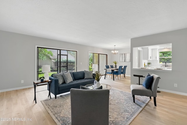 10136 Leisure Ln N Unit 26, Jacksonville, FL 32256 - living area featuring a chandelier, light wood-style flooring, baseboards, and a textured ceiling