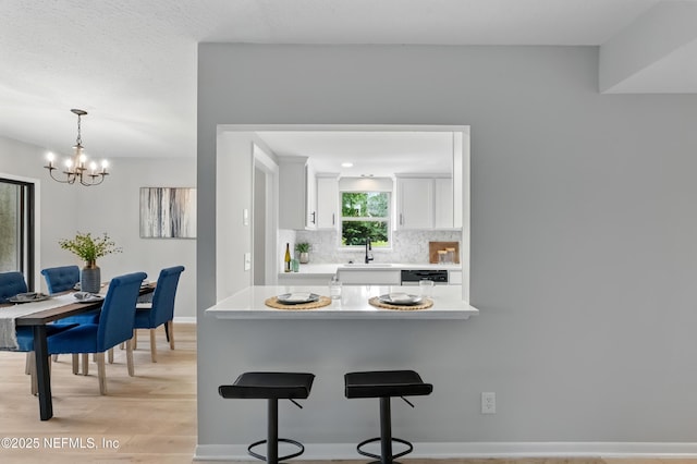 10136 Leisure Ln N Unit 26, Jacksonville, FL 32256 - kitchen featuring a kitchen breakfast bar, light wood-type flooring, light countertops, white cabinets, and a chandelier
