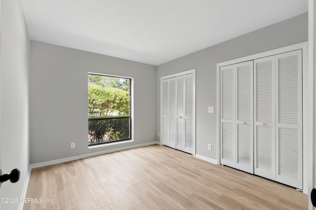 10136 Leisure Ln N Unit 26, Jacksonville, FL 32256 - unfurnished bedroom featuring multiple closets, light wood-style flooring, and baseboards