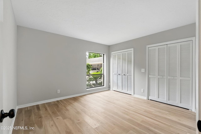 10136 Leisure Ln N Unit 26, Jacksonville, FL 32256 - unfurnished bedroom featuring multiple closets, light wood finished floors, and baseboards
