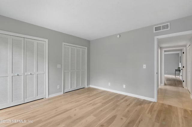 10136 Leisure Ln N Unit 26, Jacksonville, FL 32256 - unfurnished bedroom with two closets, light wood finished floors, and baseboards