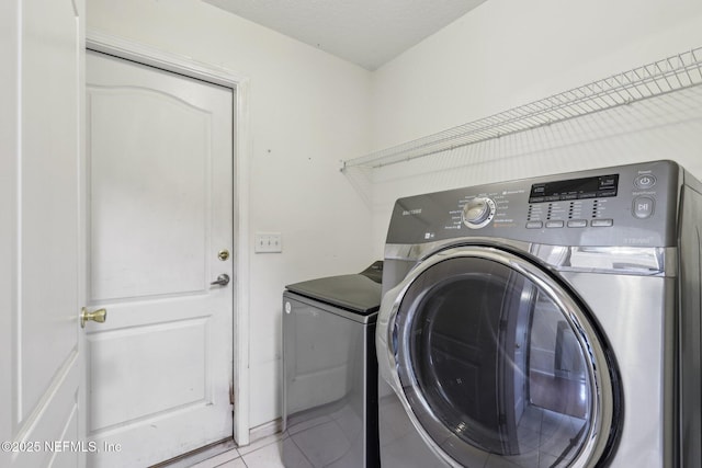 laundry area featuring laundry area, light tile patterned floors, and washing machine and clothes dryer