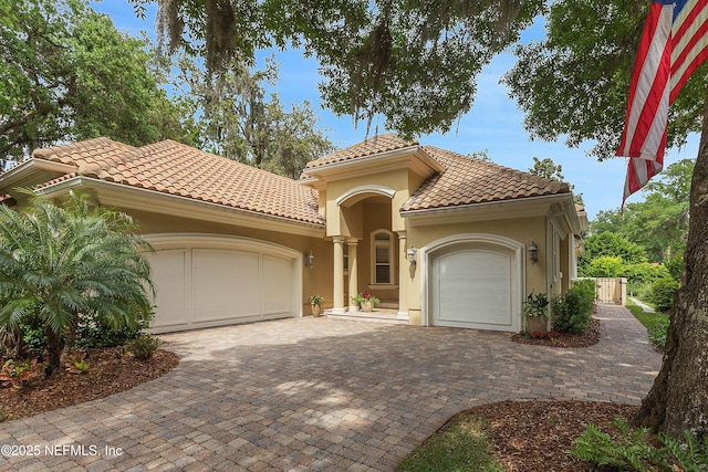 101 Dahlia Ct, Ponte Vedra Beach, FL 32082 - mediterranean / spanish house featuring an attached garage, decorative driveway, a tiled roof, and stucco siding