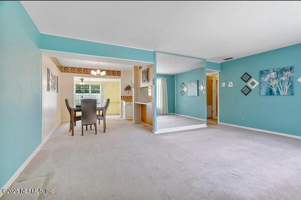 dining room with carpet, a notable chandelier, and baseboards