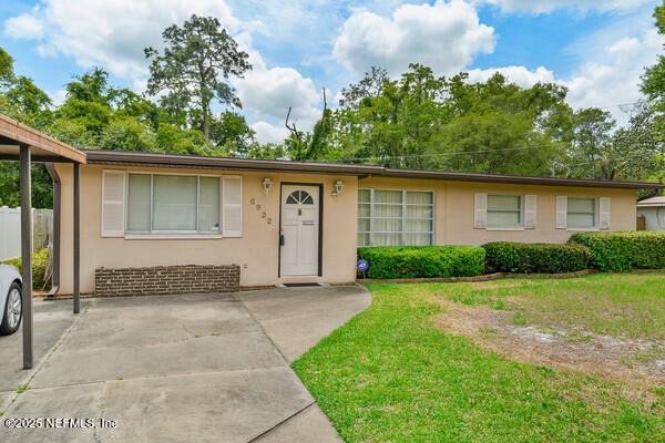 ranch-style home featuring stucco siding and a front lawn