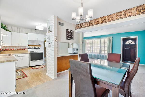 dining area featuring baseboards, visible vents, light wood-type flooring, and an inviting chandelier