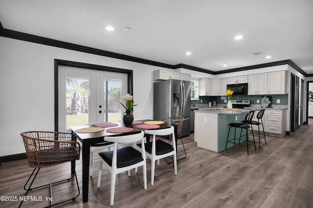 dining space with french doors, visible vents, crown molding, wood finished floors, and recessed lighting