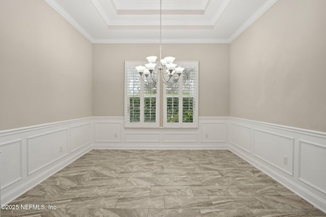 unfurnished room featuring a wainscoted wall, a raised ceiling, a notable chandelier, a decorative wall, and ornamental molding