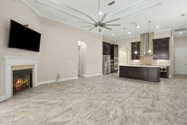 kitchen with stainless steel appliances, arched walkways, open floor plan, visible vents, and wall chimney range hood