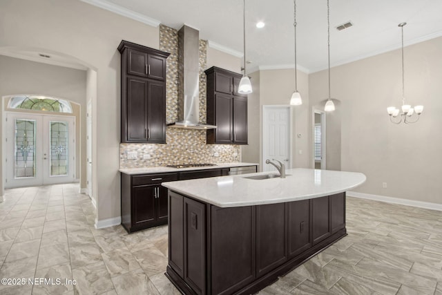kitchen with light countertops, visible vents, a sink, arched walkways, and wall chimney exhaust hood