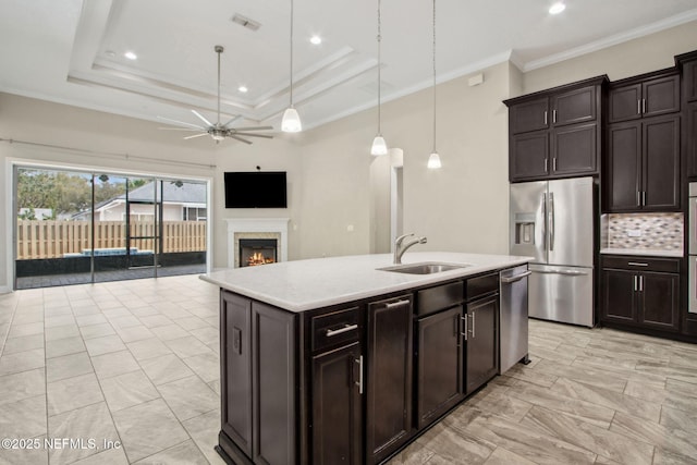 kitchen featuring a ceiling fan, a sink, a lit fireplace, stainless steel appliances, and light countertops