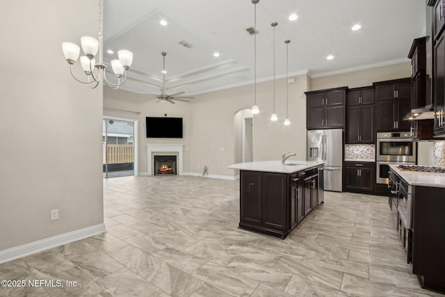 kitchen featuring open floor plan, arched walkways, light countertops, decorative light fixtures, and appliances with stainless steel finishes