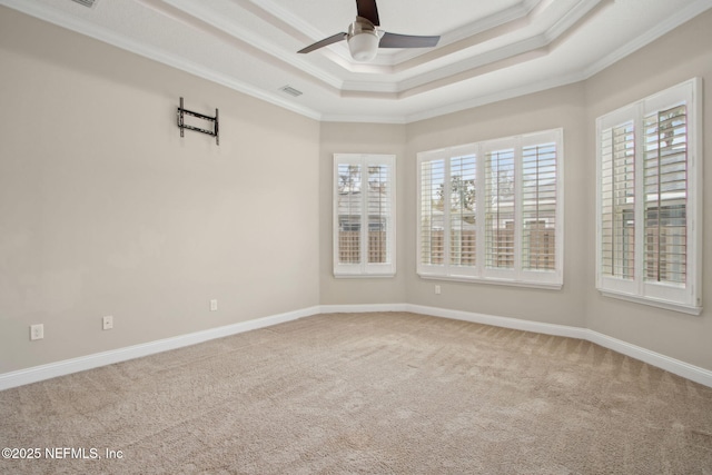 empty room featuring ceiling fan, ornamental molding, a tray ceiling, and visible vents