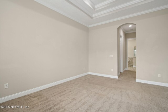 empty room with a tray ceiling, arched walkways, baseboards, crown molding, and carpet floors