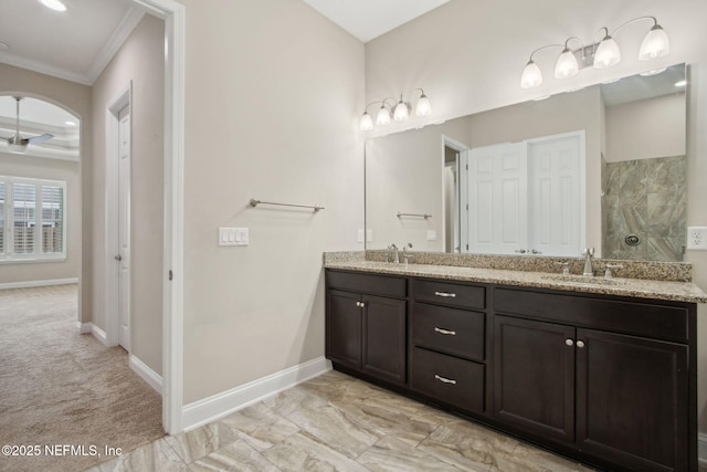 full bath with double vanity, crown molding, baseboards, and a sink