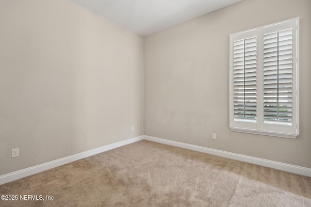 carpeted empty room featuring baseboards