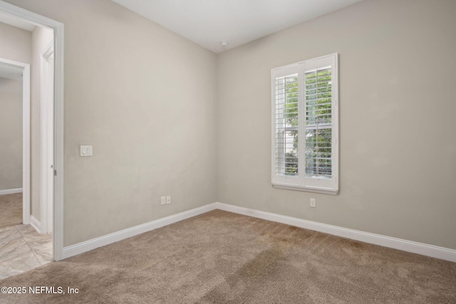 spare room featuring baseboards and light colored carpet