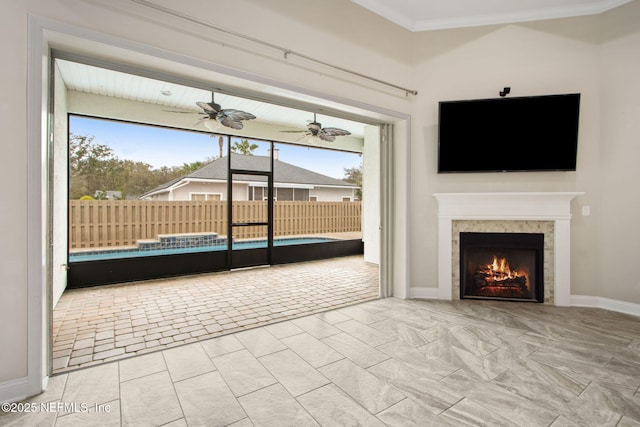 unfurnished living room with baseboards, a healthy amount of sunlight, crown molding, and a fireplace