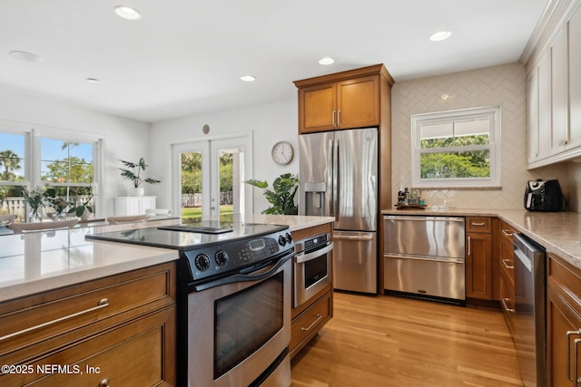 kitchen featuring decorative backsplash, light wood-style flooring, stainless steel appliances, recessed lighting, and brown cabinetry
