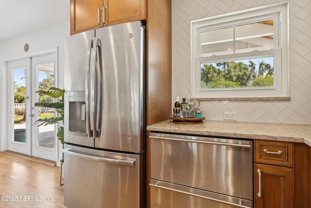 kitchen with light stone countertops, brown cabinets, appliances with stainless steel finishes, and decorative backsplash