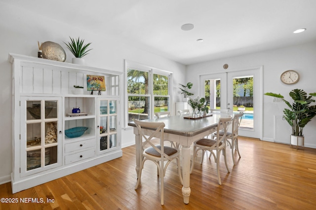 dining area featuring light wood finished floors, french doors, and baseboards