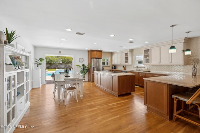 kitchen with visible vents, light wood-type flooring, brown cabinetry, and a sink