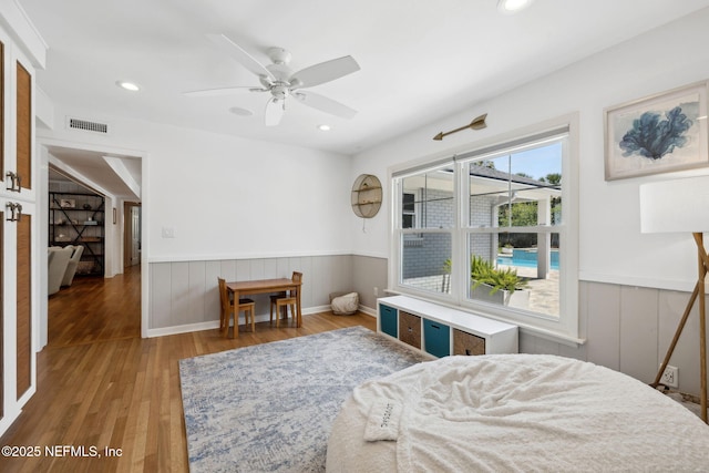 bedroom with recessed lighting, visible vents, wainscoting, and wood finished floors