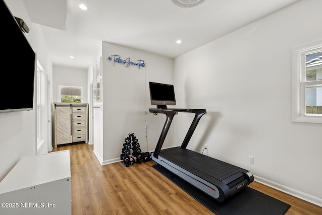 workout room featuring a healthy amount of sunlight, light wood-type flooring, and baseboards