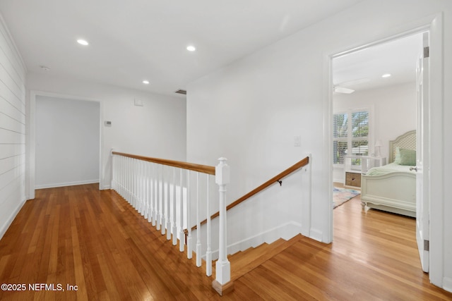 corridor with recessed lighting, wood finished floors, an upstairs landing, baseboards, and visible vents